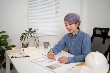 Asyalı kadınlar iş yerinin tasarım planı ve emlak geliştirme ya da Emlak İşletmeleri konsepti için taslak taslağı hazırlıyorlar. Bina Tasarımı Gayrimenkul için çok önemli.