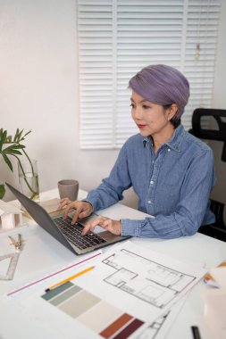 Ev planı projesi için dizüstü bilgisayarda çalışan Asyalı kadın mimar Asyalı kadın mimar. Profesyonel iç tasarım yönetimi projesi ev yenileme düzeni inşaatı.