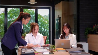 Modern bir ofiste iş birliği yapan üç Asyalı kadın. Bu sahnede takım çalışması, proje tartışması ve ortak bir atmosfer sergileniyor. Şirket kültürünü ve başarısını resmetmek için mükemmel..