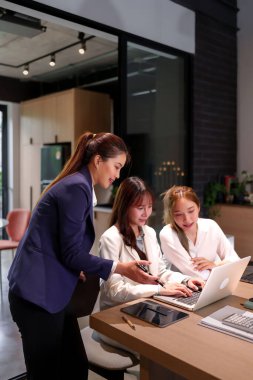 Dizüstü bilgisayarda çalışan bir grup Asyalı genç kadın ofiste iş projesini tartışıyorlar. Yeni başlayan şirket için takım çalışması. Beyin fırtınası fikirleri ve strateji çözümleri.