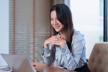 İş toplantısında gülümseyen genç bir Asyalı kadın dizüstü bilgisayarındaki bir video görüşmesine katılıyor. Çevrimiçi konferans ya da sanal sunum sırasında mutlu çalışan. Takım üyesi