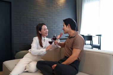 Asyalı genç bir çift evlerindeki kanepede oturmuş özel bir olayı kutluyorlar. Kadehlerini kırmızı şarap kadehleriyle kaldırıyorlar. Birlikte aşk ve neşeyi paylaşıyorlar..