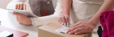 Yetişkin Asyalı kadınlar evde küçük bir iş için tablet kullanırken teslimat için bir paket hazırlıyorlar. Bu bir çevrimiçi alışveriş e-ticaret ve lojistik konseptini somutlaştırmaktadır.