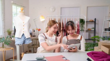 İki genç Asyalı kadın internet üzerinden küçük işletmelerini yönetiyor, tabletle sipariş alıyor, müşterilerle telefonla konuşuyor, envanterleri kontrol ediyor ve eve nakliye için paketler hazırlıyorlar..