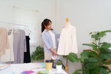 Genç bir Asyalı moda tasarımcısının yeni giysi koleksiyonu için bir mankenin üzerindeki giysiyi düzenleme sürecini keşfedin. Moda ve giysi hakkında bilgi edinin..