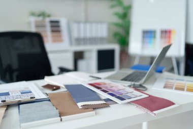 Parlak bir çalışma alanı üzerinde kumaş örnekleri ve renk paletleri kullanarak iç tasarım kavramlarını araştırın. İlham bulun ve yenileme için maddi seçimler yapın.