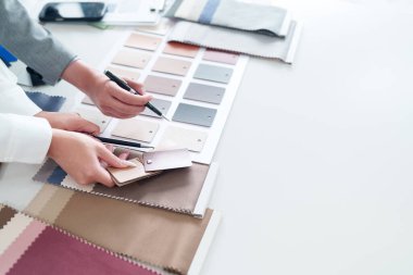 İç mimar Asyalı yetişkin elleri malzeme örnekleri seçiyor ve ev yenileme projesi üzerine fikirler yazıyor. Renk palet kumaş ve ahşap kaplama seçimi.