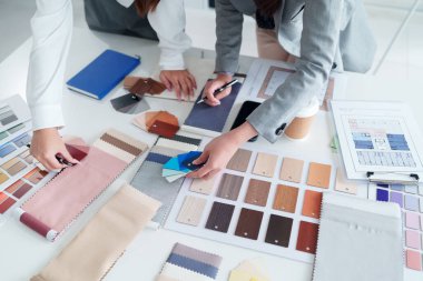 İç mimarlar renk örnekleri ve malzeme örnekleri seçerek bir tasarım projesinde işbirliği yapıyorlar. Yetişkin Asyalı kadın mimarların elleri ev dekoru seçimi üzerinde çalışıyor..