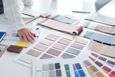 Yetişkin Asyalı kadın elleri, ofisteki mimari iç tasarım için masadan renk örnekleri seçiyor. Kumaşlı çalışma alanı.