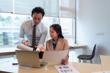 Asyalı iş adamları veri analizi raporunu inceliyor. Belge dizüstü bilgisayarı strateji bürosu işbirliği, profesyonel iş yerini tartışıyor.