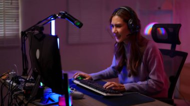 Mutlu Asyalı genç bayan flamalı ev ortamında rekabetçi oyun oturumunun keyfini çıkarıyor.