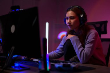 Kulaklık takarak bilgisayar üzerinden video oyunu oynayan Asyalı kadın flama.