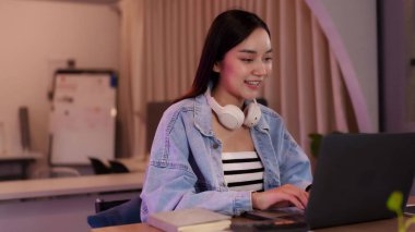 Kendine güvenen Asyalı kadın, şık bir iş yerinde bilgisayarında çalışıyor. Esnek bir dijital iş hayatı var..