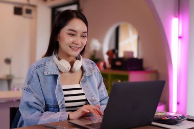 Genç Asyalı kadın güvenli bir şekilde laptopta çalışıyor. O mutlu ve uzaktan çalışma esnekliğini kucaklamaya odaklanmış. Modern dijital girişimcilik.