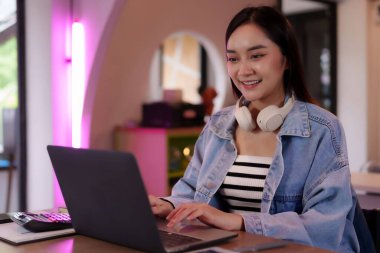 Bilgisayarda çalışan mutlu Asyalı kadın uzaktan çalışmayı ve dijital göçebe özgürlüğünü benimsiyor.