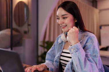 Üretken Asyalı kadın canlı çalışma alanında uzaktan çalışmaktan zevk alıyor. Bilgisayarına odaklanmış, esnek çalışma dijital göçebe yaşam tarzını benimsiyor..