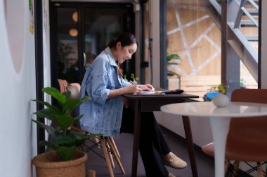 Asyalı kadın, iş yerinde rahat bir ofis ortamında verimli bir iş yapıyor. Serbest meslek sahipleri ve iş birliği yapmak isteyen uzak işçiler için ideal..