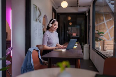 Genç Asyalı kadın bilgisayarını dijital göçebe işi için başarıyla kullanıyor. Çevrimiçi iş işleri için rahat çalışma alanlarının keyfini çıkarın.