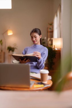 Huzurlu bir Asyalı kadın bir kitaba daldı. Rahatlamak için mükemmel bir ortam yarattı. Kişisel gelişim ve kapalı alanda öğrenme için.