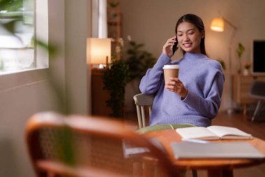 İçerik sahibi Asyalı genç bir kadın cep telefonuyla ev telefonuna cevap veriyor. Kahvesini içiyor. Özel rahat yaşam tarzı anları yaşıyor.