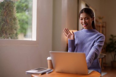 Gülümseyen Asyalı kadın uzaktan kumandayla iletişim kuruyor.