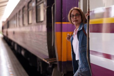 Yaşlı Asyalı kadın kurullar tren istasyonu macera serüveni. Varış yeri toplu taşımacılık emeklilik özgürlük turizm yaşam tarzı seyahat.
