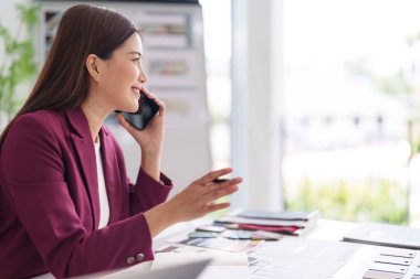 Gülümseyen Asyalı yetişkin kadın iş görüşmesi yapıyor tasarım planlarını tartışıyor emlak satışları profesyonel ofis ortamı
