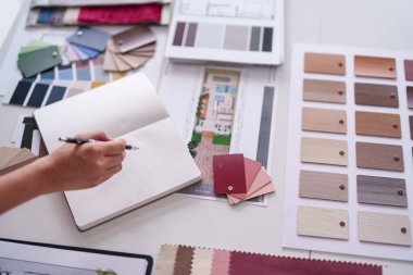 Profesyonel mimar el, çeşitli kumaş ve planlardan beyaz bir tabloda detaylı ev tasarımı seçici materyaller oluşturur.