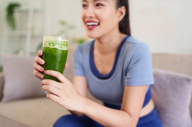 Neşeli Asyalı kadınlar besin değeri yüksek yeşil meyve sularının keyfini çıkararak aktif sağlıklı yaşamı ve doğal refahı destekliyor.