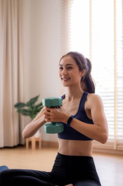 Asyalı kadın, evde ağırlık egzersizi yapıyor. Güçlü bir vücut ve genel olarak sağlıklı olmayı teşvik ediyor. Sağlıklı yaşam için günlük egzersiz rutini.