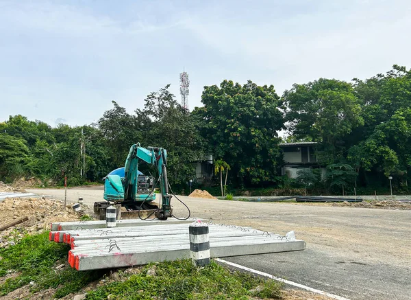 Mavi kazıcı ve beton turtaları olan yol şantiyesi, Tayland.