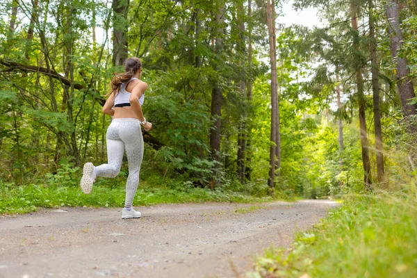高强度间歇训练中在林间路上跑步的女运动员的背景图 — 图库照片