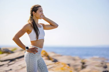 Güneşli bir günde açık gökyüzüne bakarken gülümseyen bayan sporcu.