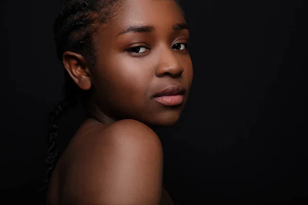 Real beautiful real woman with dark skin on black bakground. High quality low-key studio portrait.