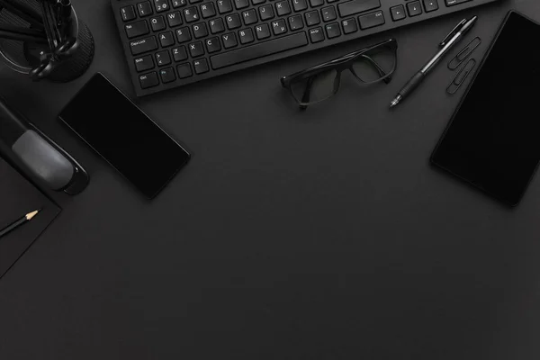 スマートフォン タブレット メガネとグレーの机の上にコンピュータのキーボードとオフィスデスクの直接上記のショット — ストック写真