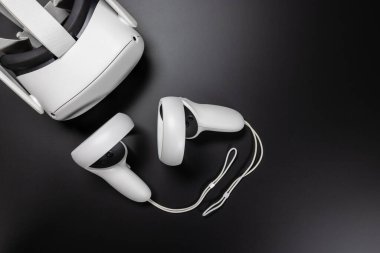 Siyah masadaki sanal gerçeklik simülatörü VR gözlükleri ile beyaz hareket denetleyicilerinin genel görünümü