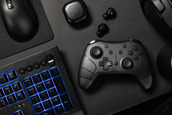 平面拍摄的各种现代游戏设备与蓝色照明键盘与咖啡杯黑色桌子 当代游戏桌面概念 — 图库照片