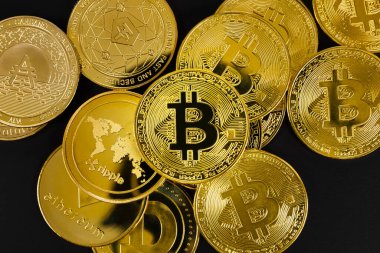 Bitcoin madeni parasının yakın plan görüntüsü siyah arkaplan üzerindeki çeşitli altın kripto para birimlerinin üzerinde