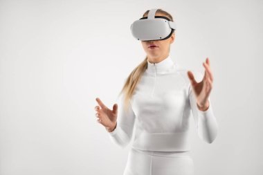 Sanal gerçeklik metaevreleri için VR gözlük takan beyaz elbiseli bir kadın. Beyaz arka planda gelecek konsepti.
