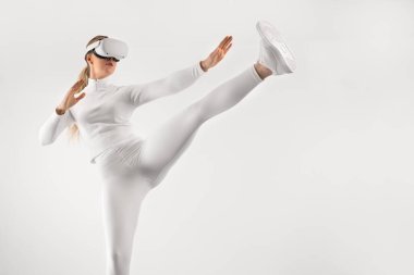 Sanal gerçeklikte metaevrende spor yapmak için VR gözlük takan fütürist görünümlü güzel bir kadın. Çağdaş ve minimalist dövüş sanatı konsepti.