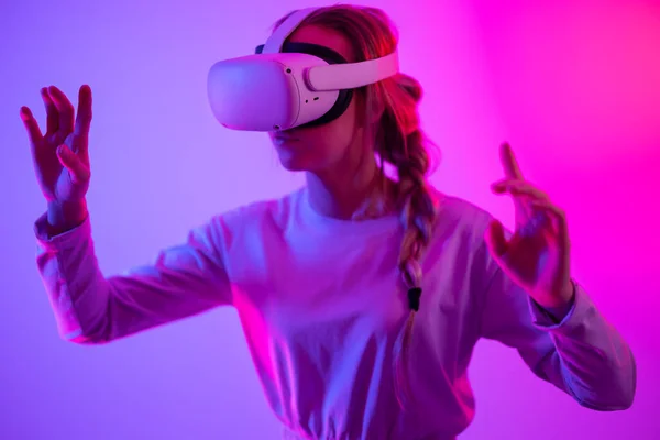 Exploring around the metaverse using VR. Young woman exploring immersive technology in a studio playing 3D game while wearing a virtual reality headset.