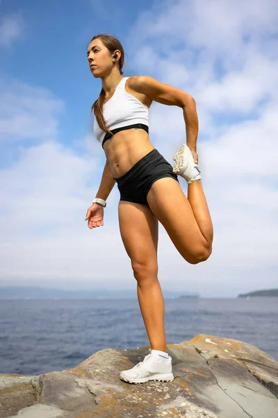 高強度のインターバルトレーニング中に岩の上でウォーミングアップ運動を行う女性選手にフィット — ストック写真