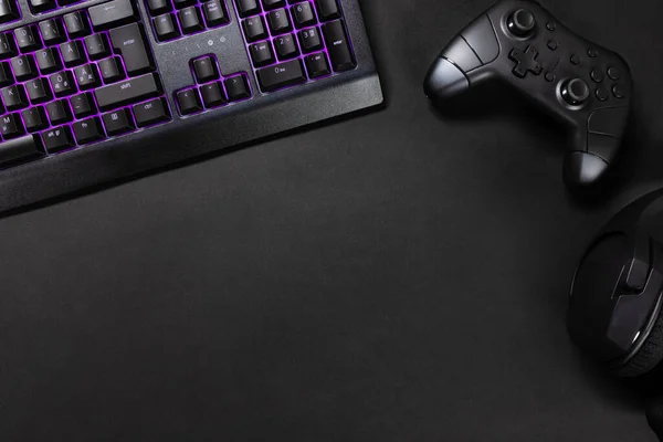 游戏控制器和鼠标直接在黑桌上观看紫色发光键盘 — 图库照片