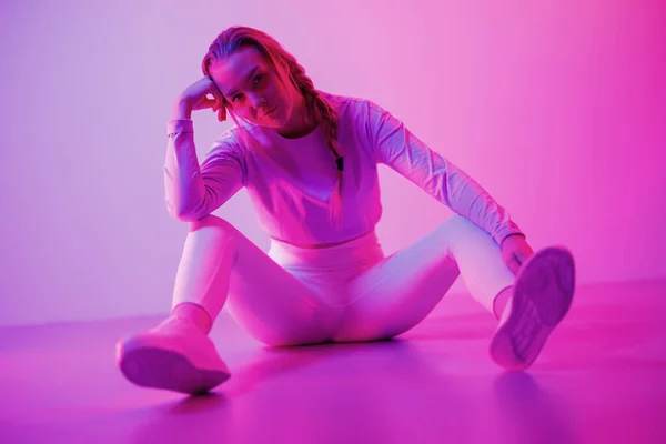 Retrato Jovem Mulher Sportswear Sentado Contra Iluminado Neon Roxo Fundo — Fotografia de Stock