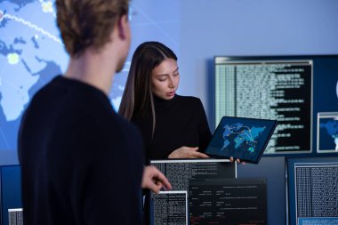 Siber Güvenlik Operasyon Merkezi SOC 'de çalışan siber güvenlik ekibi. Kadın Bilgi Güvenliği Şefi CISO olarak çalışıyor ve müdür gerçek zamanlı bir harita om tabletine işaret ediyor.