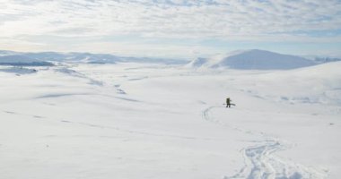 Bir adam güzel güneşli bir günde Norveç 'in Dovre ya da Dovrefjell dağlarında yürüyüş yapıyor. Uçsuz bucaksız kar ve vahşi doğa..