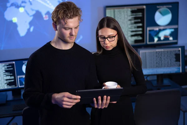stock image Two focused professionals in cyber security team working to prevent security threats, find vulnerability and solve incidents. Woman pointing on a event map.
