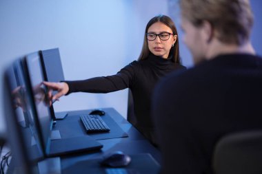 Cybersecurity professionals collaborating and analyzing network security data on computer monitors in a modern office setting. clipart