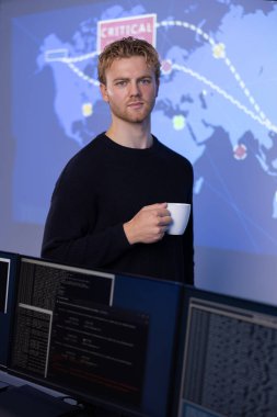 Portrait of a confident man working as a Cyber Security Analyst in a Security Operation Center SOC. Map and SIEM system in the background. Holding a coffee cup in front of risk map. clipart