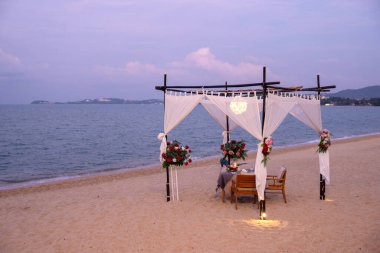 Okyanusa bakan kumlu bir plajda ahşap dekorlu zarif bir yemek düzeni..